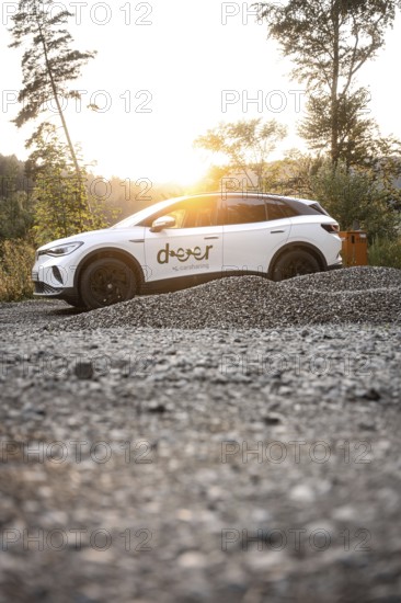 White car at sunset on gravel surrounded by nature, peaceful atmosphere, VW ID4 electric car, deer car sharing, Calw, Germany