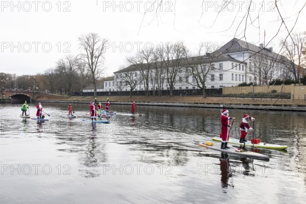 Water sports enthusiasts dressed up as Santa Claus ride SUPs on the Spree in front of Bellevue Palace in Berlin on 30.11.2025