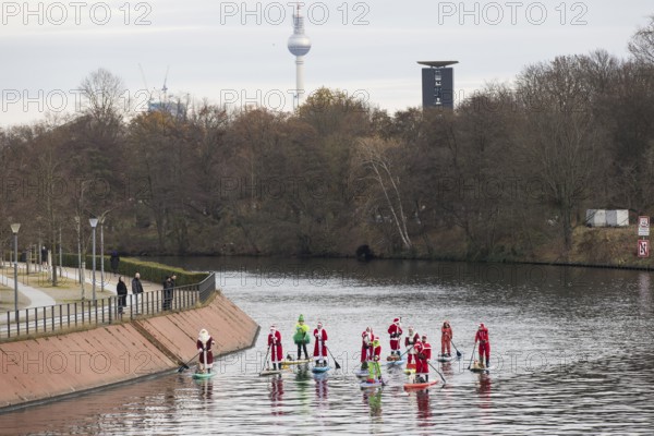 Water sports enthusiasts dressed up as Santa Claus ride SUPs on the Spree am Park at the presidential triangle in Berlin on 30.11.2025
