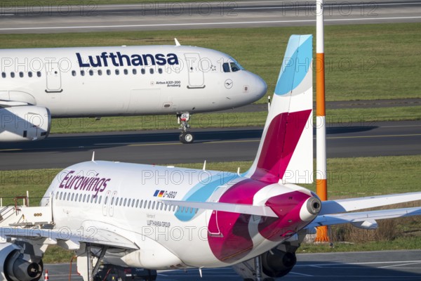 Lufthansa Airbus A321-200 on taxiway for takeoff, Eurowings Airbus parks outside position, Düsseldorf airport, DUS