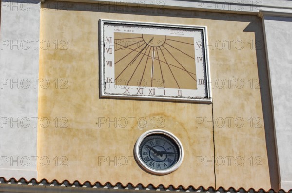 Sundial above and below masonry clock with hands, Italy