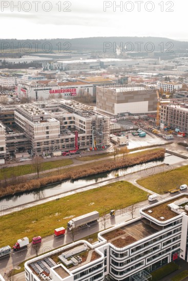 Urban construction site with buildings and river in the foreground under overcast sky, Böblingen, Germany