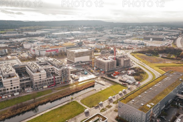 New hospital construction site with buildings and cranes near a river under cloudy sky, Böblingen, Germany