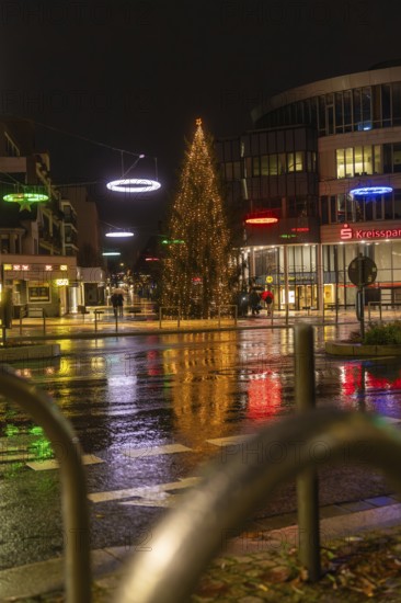 Large illuminated Christmas tree surrounded by colorful street lights in rainy city at night, Böblingen Christmas market, Germany