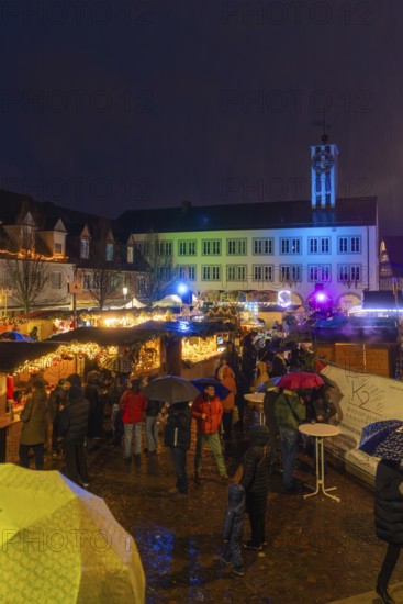Colourfully lit Christmas market with people and umbrellas in a nighttime urban landscape, Böblingen Christmas market, Germany