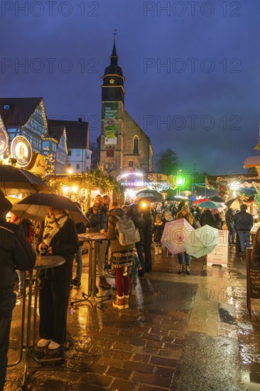 Lively Christmas market in rain with people and illuminated church in the background, Böblingen Christmas market, Germany