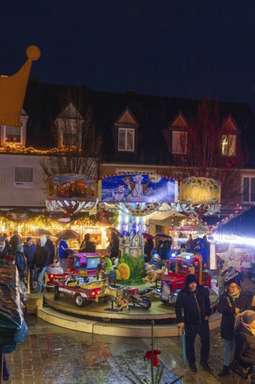 Families in front of an illuminated carousel with toys at a night-time Christmas market, Böblingen Christmas market, Germany