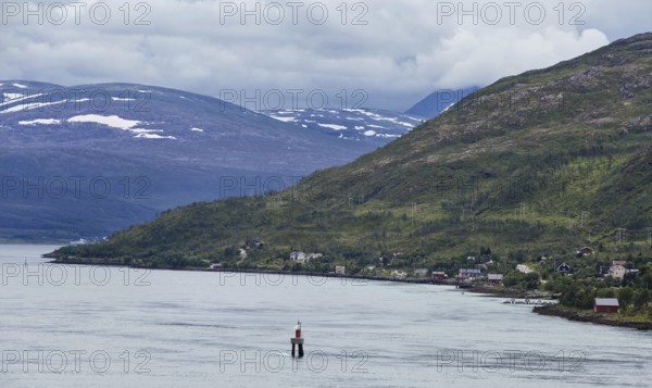 A quiet coastal strip with scattered villages in wooded hills and foggy skies, Norway