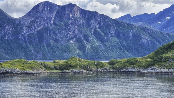 Rocky mountain landscape on a quiet fjord with grassy shores, Norway