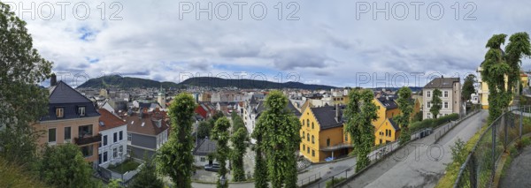 View of the city of Bergen with colorful houses and hills under a cloudy sky, Bergen Norway