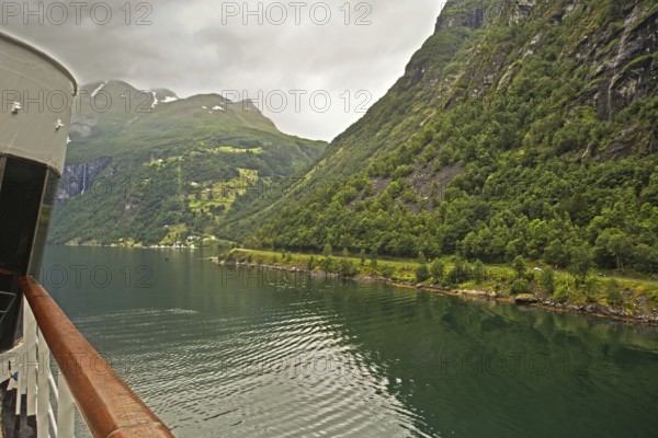 Scenic view of a fjord with forested mountains in the background and a ship in the foreground, Norway