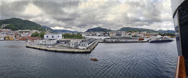 Extensive view of a harbor with ships and surrounding wooded mountains, mountains