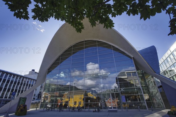 Modern glass architecture under a bright sky showing the entrance of a library in an urban setting, Tromso