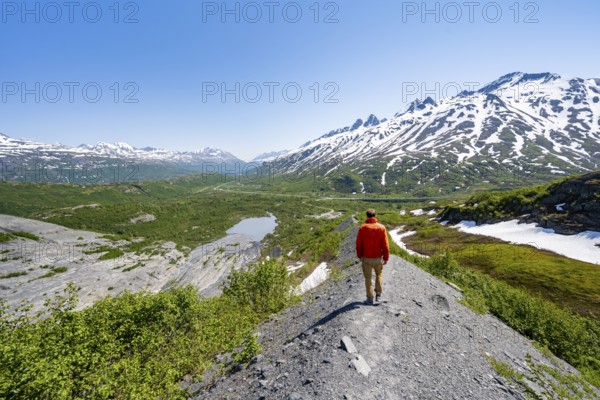 Hikers on glacial moraine, view of the vast Tsina River valley with mountains, Worthington Glacier Lagoon, Worthington Glacier State Recreational Site, Chugach Mountains, Alaska, USA