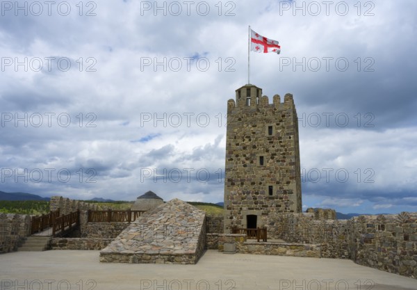 Stone castle with tower and Georgian flag on a plateau under cloudy sky, Rabati Fortress, Akhaltsikhe, Samtskhe-Javakheti region, Samtskhe-Javakheti, Georgia