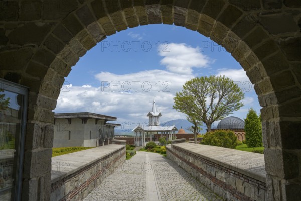 Buildings seen through a stone arch, with a cloudy sky and trees, Rabati Fortress, Akhaltsikhe, Samtskhe-Javakheti region, Samtskhe-Javakheti, Georgia