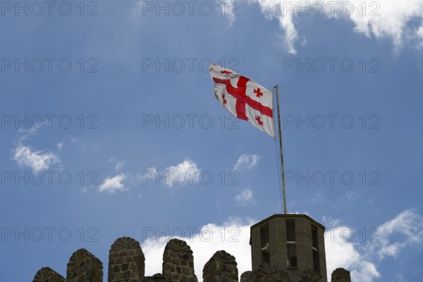 Georgian flag flying on a stone tower under blue sky with clouds, Rabati Fortress, Akhaltsikhe, Samtskhe-Javakheti region, Samtskhe-Javakheti, Georgia