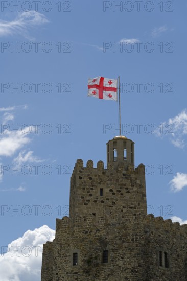 A stone castle with a Georgian flag flies on the tower against a clear blue sky, Rabati Fortress, Akhaltsikhe, Samtskhe-Javakheti region, Samtskhe-Javakheti, Georgia