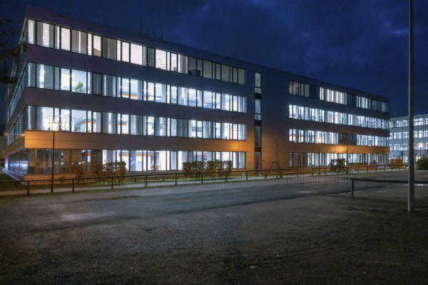 Siemens office buildings illuminated in the evening, empty parking spaces in front, Erlangen, Middle Franconia, Bavaria, Germany