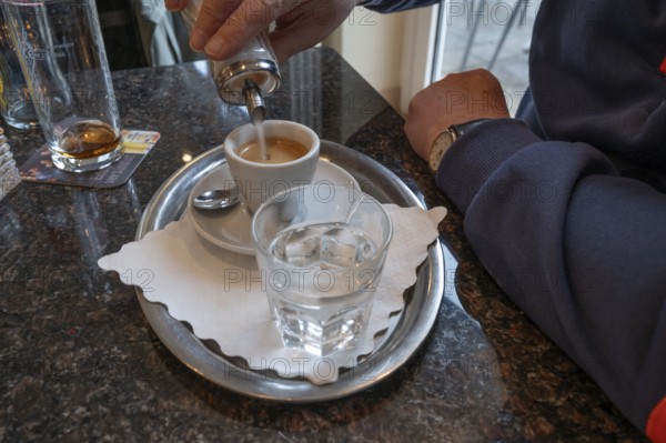 A guest sweetens his espresso in a café, Lauf an der Pegnitz, Middle Franconia, Bavaria, Germany