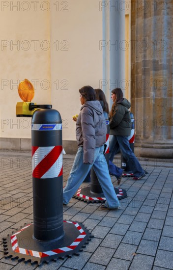 Passers-by at the security barrier made of massive bollards at the Brandenburg Gate passage, Berlin, Germany