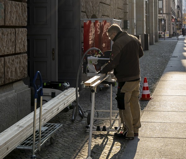 Craftsman with circular saw in the open air, Jägerstraße Berlin, Germany