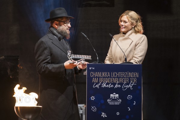 Julia Klöckner (President of the German Bundestag) receives a gift from Yehuda Teichtal (Rabbi of the Chabad-Lubavitch movement) at the lighting of lights to mark 20 years of Hanukkah in front of the Brandenburg Tor, Berlin, 17 December 2025