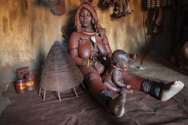 Himba woman sitting with baby, Himba perfume, scented smoke from burning plants, Himba village, Kaokoveld, Kunene, Namibia