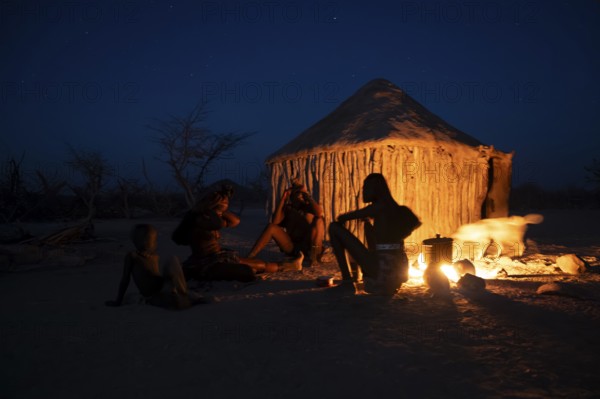 Himba at the campfire in the evening, night view, Himba huts, traditional Himba village in the savanna, Kaokoveld, Kunene, Namibia