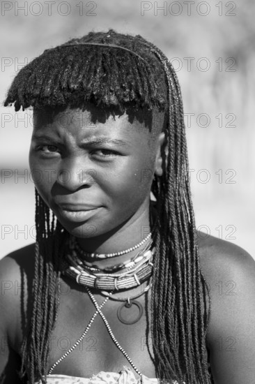 Black and white, portrait, brightly decorated woman of the Hakaona tribe, also Havakona or Hakawona, near Opuwo, Kunene, Namibia