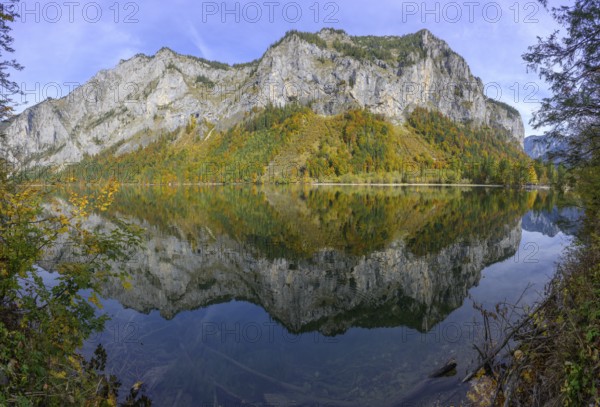 Rocks and autumn forest are reflected in the water of Lake Leopoldstein, Eisenerz, Styria, Austria