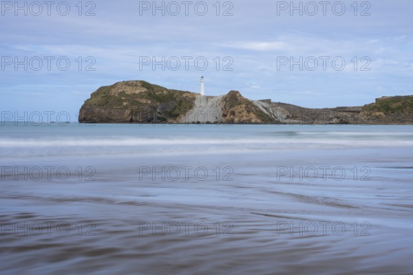 Castlepoint Beach, ocean and lighthouse on a rock, long exposure. Castlepoint, Wairarapa Coast, Wellington Region, North Island, New Zealand