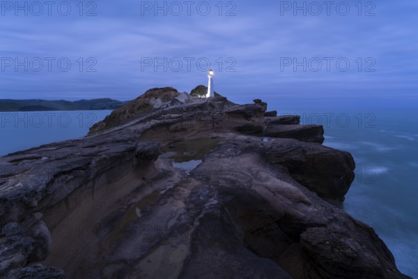 Castlepoint lighthouse on a rock, ocean, evening, blue hour, illuminated, long exposure. Castlepoint, Wairarapa Coast, Wellington Region, North Island, New Zealand