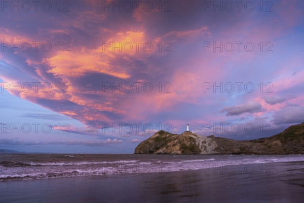 Castlepoint Beach, ocean and lighthouse on a rock, evening, sunset, dramatic sky. Castlepoint, Wairarapa Coast, Wellington Region, North Island, New Zealand