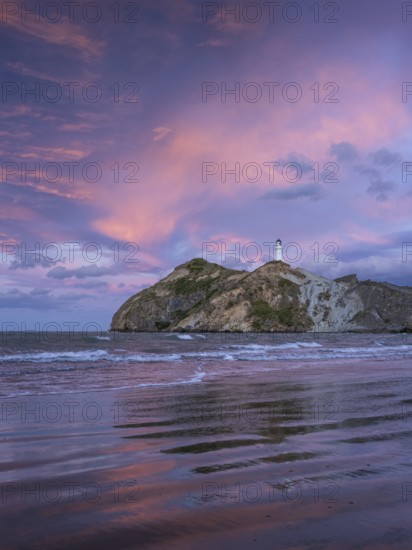 Castlepoint Beach, ocean and lighthouse on a rock, evening, sunset, dramatic sky. Castlepoint, Wairarapa Coast, Wellington Region, North Island, New Zealand