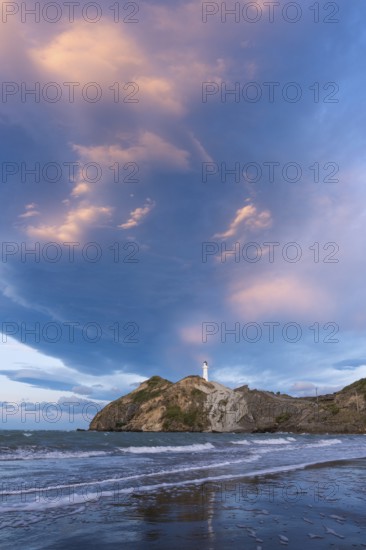 Castlepoint Beach, ocean and lighthouse on a rock, in the evening, dramatic sky. Castlepoint, Wairarapa Coast, Wellington Region, North Island, New Zealand