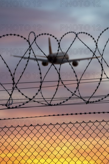 Airplane taking off over barbed wire at sunset, colorful sky, Stuttgart airport, Leinfelden-Echterdingen, Baden-Württemberg, Germany