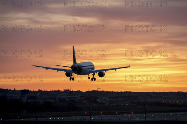 Airplane approaching runway at sunset, orange sky in background, Stuttgart airport, Leinfelden-Echterdingen, Baden-Württemberg, Germany