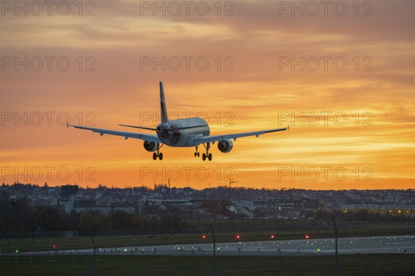 Airplane flying over illuminated runway at sunset, Stuttgart Airport, Leinfelden-Echterdingen, Baden-Württemberg, Germany