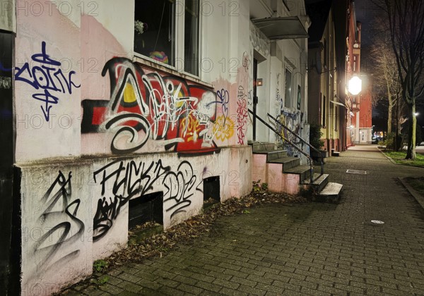 Facade covered with graffiti at night in a problem district, no-go area in Gelsenkirchen, one of the poorest cities in Germany
