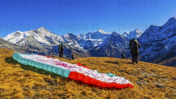 Paragliders are preparing for their start, with the snow-capped peaks of the Valais Alps, Val d'Anniviers, Canton of Valais, Switzerland