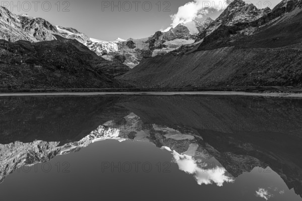 The Moiry glacier and mountain peaks are reflected in Lac de Chateaupre, black and white photo, Val d'Anniviers, Valais Alps, Canton of Valais, Switzerland