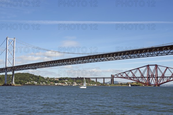 Two distinctive bridges over water with a small sailboat in the foreground, railway bridge and road bridge, Firth of Forth, Edinburgh, Scotland, Great Britain