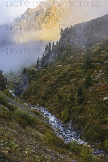 Small stream flows from Lac de Moiry reservoir to Grimentz, mountain slopes in the evening light, Val d'Anniviers, Valais Alps, Canton of Valais, Switzerland