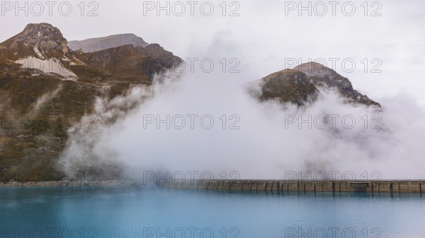Fog rises over the dam of the Lac de Moiry Reservoir, Val d'Anniviers, Valais Alps, Canton of Valais, Switzerland