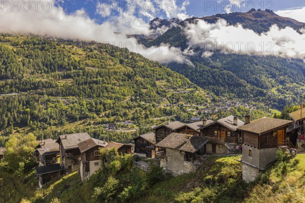 Old farmhouses in Pinsec, fog rising behind in the Val d'Anniviers, Valais Alps, Canton of Valais, Switzerland