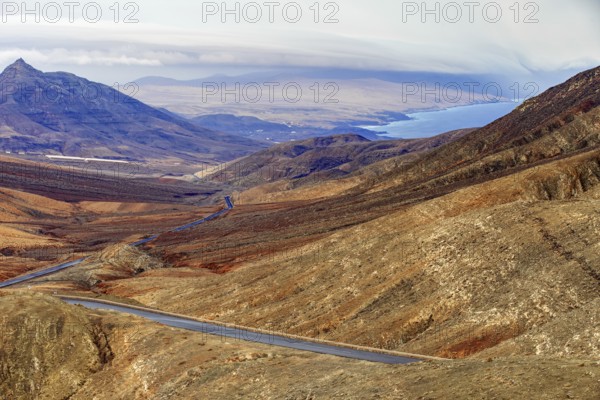 Road leads through the mountainous landscape of Fuerteventura with extensive views over the sea, Pajara Fuerteventura