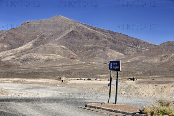 Lonely volcanic landscape with a sign to the beach under clear skies, Playa Blanca Lanzarote, Canary Island