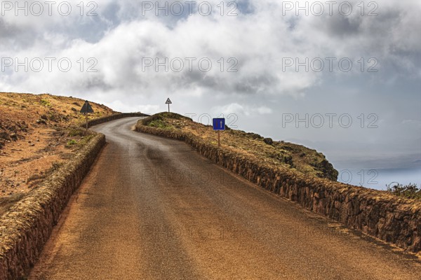 Secluded road along a rocky coast under a cloudy sky, Haria Lanzarote, Canary Island