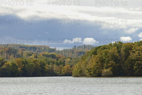 View over Lake Möhnesee, mixed autumn forest on the shore, rising rain clouds, Möhnetalsperre, North Rhine-Westphalia, Germany